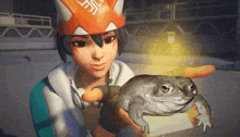 a girl holding a frog with an orange hat that says ' samurai ' on it