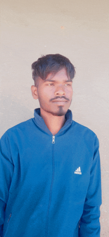 a young man wearing a blue adidas jacket