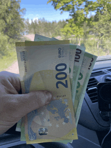 a person is holding up a stack of 200 euro bills