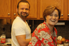 a man and a woman are smiling in a kitchen with a bottle of ranch dressing on the counter