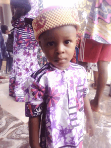 a young boy wearing a purple shirt and a hat with a crown on his head