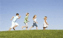 a group of children are running on top of a lush green hill .