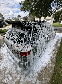 a car is covered in foam while being washed in a driveway