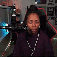 a woman wearing headphones is sitting in front of a microphone with a sign that says she shed in the background