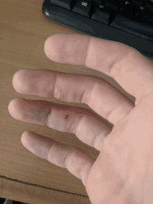 a close up of a person 's hand with a keyboard behind it