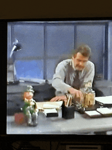 a man sits at a desk with a leprechaun figurine