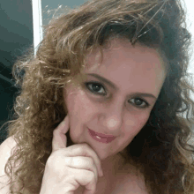 a woman with curly hair has her hand on her face