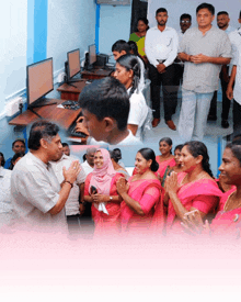 a group of people in a room with computers and a man in a white shirt