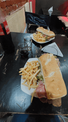 a bottle of coca cola sits on a table next to a plate of french fries