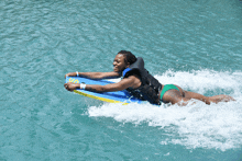 a woman in a life vest is riding a boogie board in the water