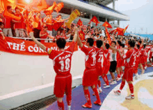 a group of soccer players are walking in front of a crowd while holding flags .