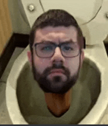 a man with a beard and glasses is sitting in a toilet with his head sticking out .