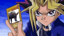 yu gi oh is a cartoon character holding a card with a picture of an elephant on it .