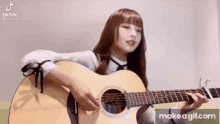 a girl is playing an acoustic guitar while singing .