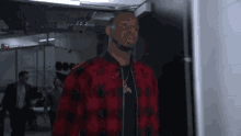 a man in a red and black plaid shirt is standing in a locker room .