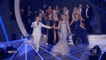 a group of people are dancing on a stage in front of a blue light .