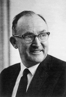 a black and white photo of a man wearing glasses and a suit