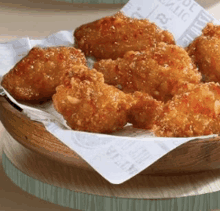 a wooden bowl filled with fried chicken wings on a piece of paper that says ' chicken ' on it