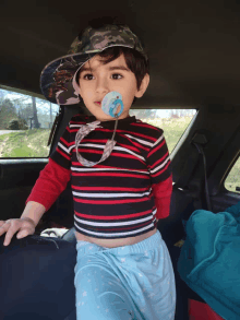 a little boy wearing a hat and a pacifier