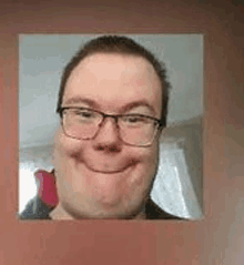 a man wearing glasses is smiling and making a funny face .