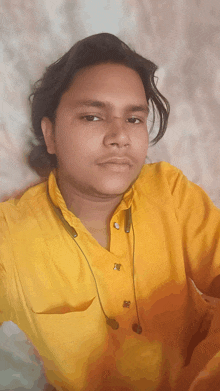 a young man wearing a yellow shirt and ear buds