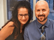 a man and a woman are posing for a picture and the man is wearing a blue shirt and tie