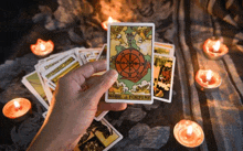 a person is holding a tarot card in front of candles .