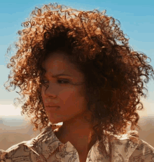 a woman with curly hair is wearing a white shirt with a pattern of horses on it