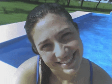 a woman in a blue bikini smiles while swimming in a pool