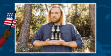 a man in a blue shirt holds a stack of bottles in his hands with a hand holding an american flag behind him