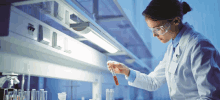 a female scientist holds a test tube with red liquid in it