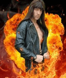 a man in a leather jacket is standing in front of a fireball .