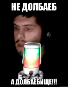 a man wearing headphones stands in front of a microphone with a colorful light behind him and says he dolbaeb