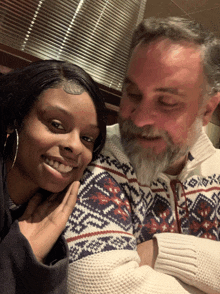 a man with a beard and a woman in a sweater are posing for a picture