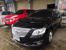 a black car with a license plate that says aa 5369 is parked in front of a red car