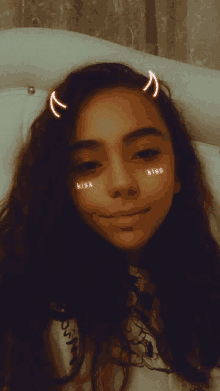 a girl with devil horns on her head and kiss written on her face