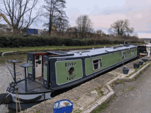 a green and black boat with the name river soar on it