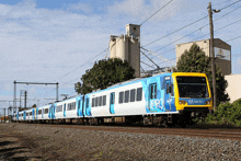 a metro train is going down the tracks near a building