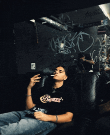 a man smoking a cigarette while wearing a black shirt that says ' badass ' on it