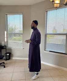 a man in a purple robe stands in front of two windows