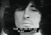 a black and white photo of a man 's face with a tcr play lock displayed