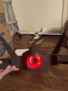 a person is holding a black object with a red light on it in front of a box that says water