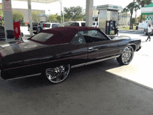 a black car with a red top is parked in front of a gas pump