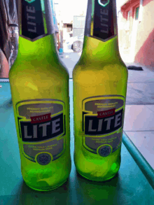 two bottles of lite castle beer are sitting on a table