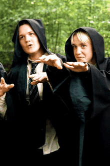 a man and a woman wearing black cloaks with hoods