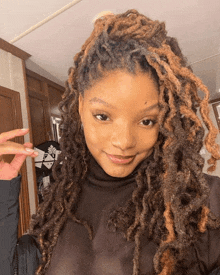 a woman with dreadlocks is wearing a black shirt and smiling