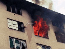 a man throws a molotov cocktail out of a window of a burning building