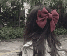 a woman with long hair and a red bow in her hair .