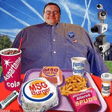 a very fat man is sitting at a table with a tray of food and drinks .