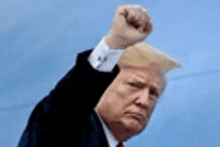 donald trump is raising his fist in the air in a close up of his face .